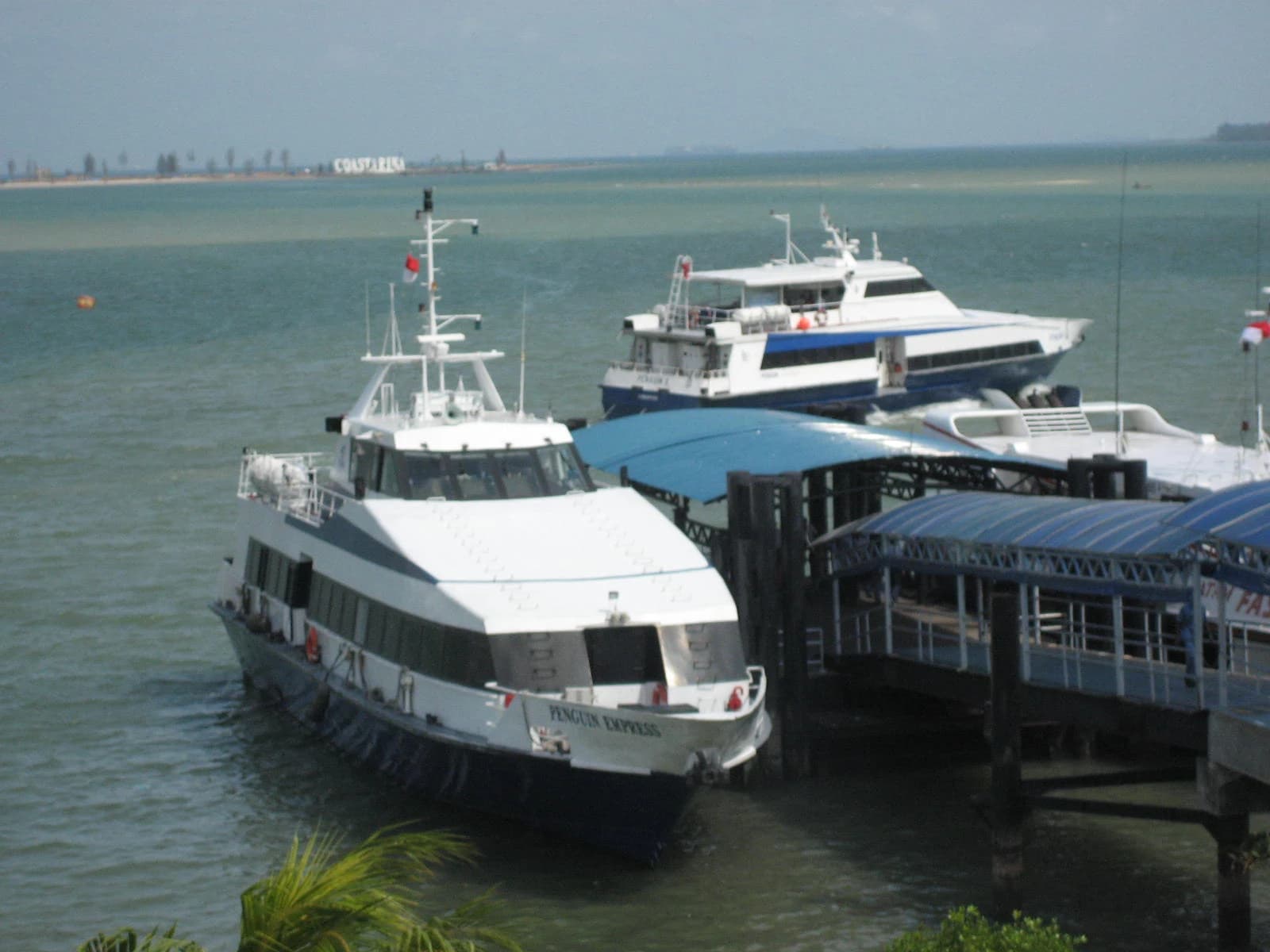 Two large white and blue ferries docked at Batam Centre Ferry Terminal.