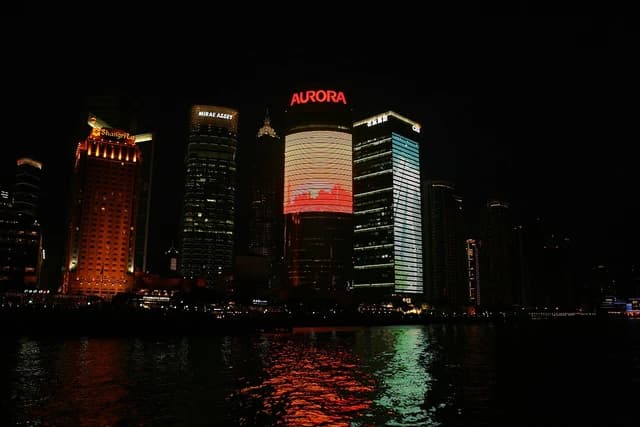 Shanghai's Bund skyline illuminated at night with skyscrapers reflected in the Huangpu River.