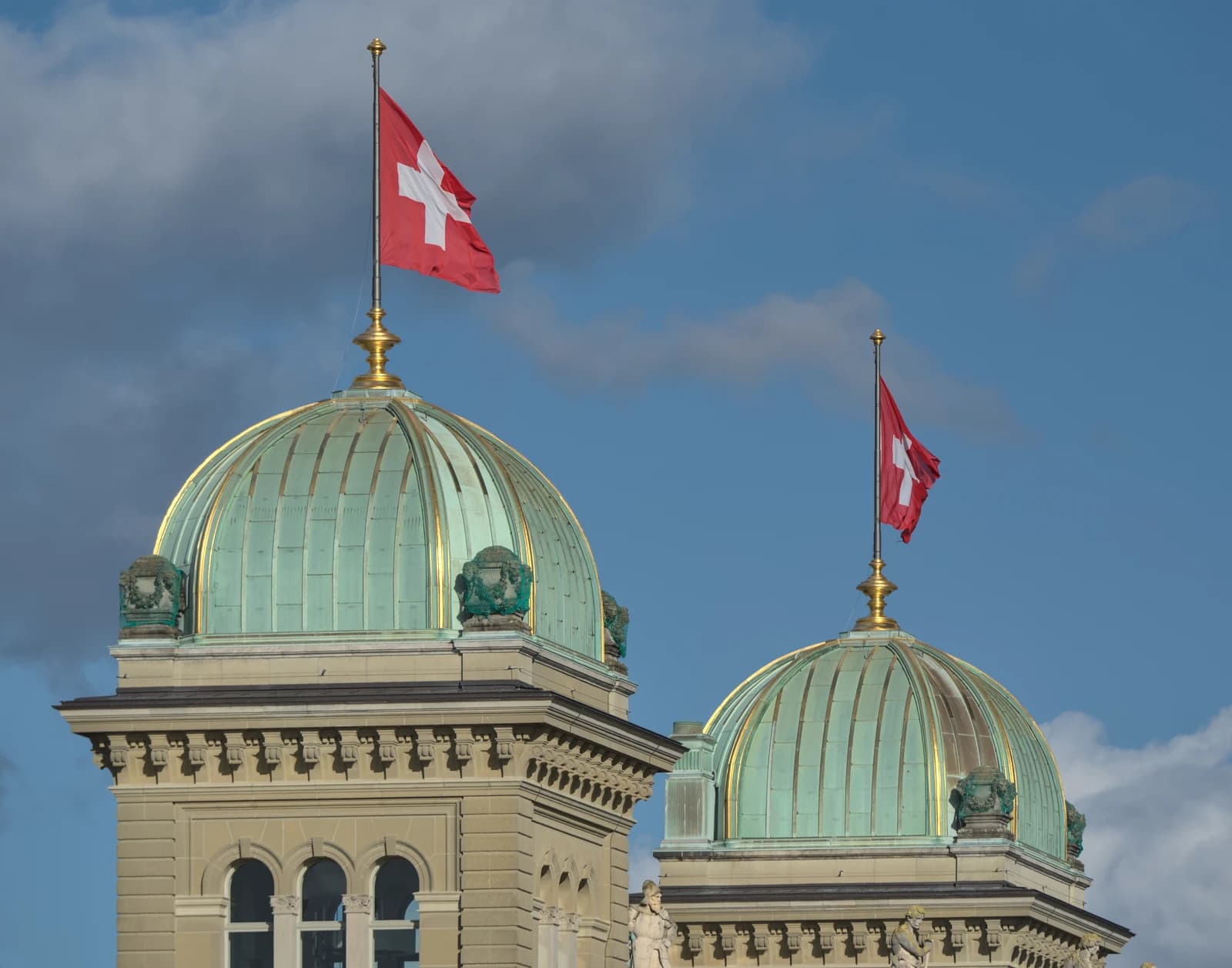 Swiss flags flying atop the domes of the Parliament Building in Bern.