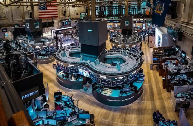 Overview of the New York Stock Exchange trading floor with desks and monitors.