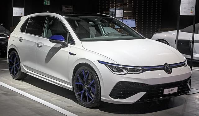 White Volkswagen Golf VIII R 20 Years car with blue accents on display.