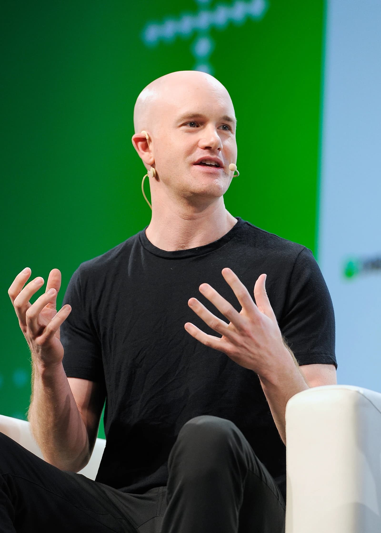 Brian Armstrong, CEO of Coinbase, speaking and gesturing with his hands at a conference.