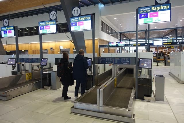 Travelers at Bergen Airport use self-service kiosks to check their luggage.