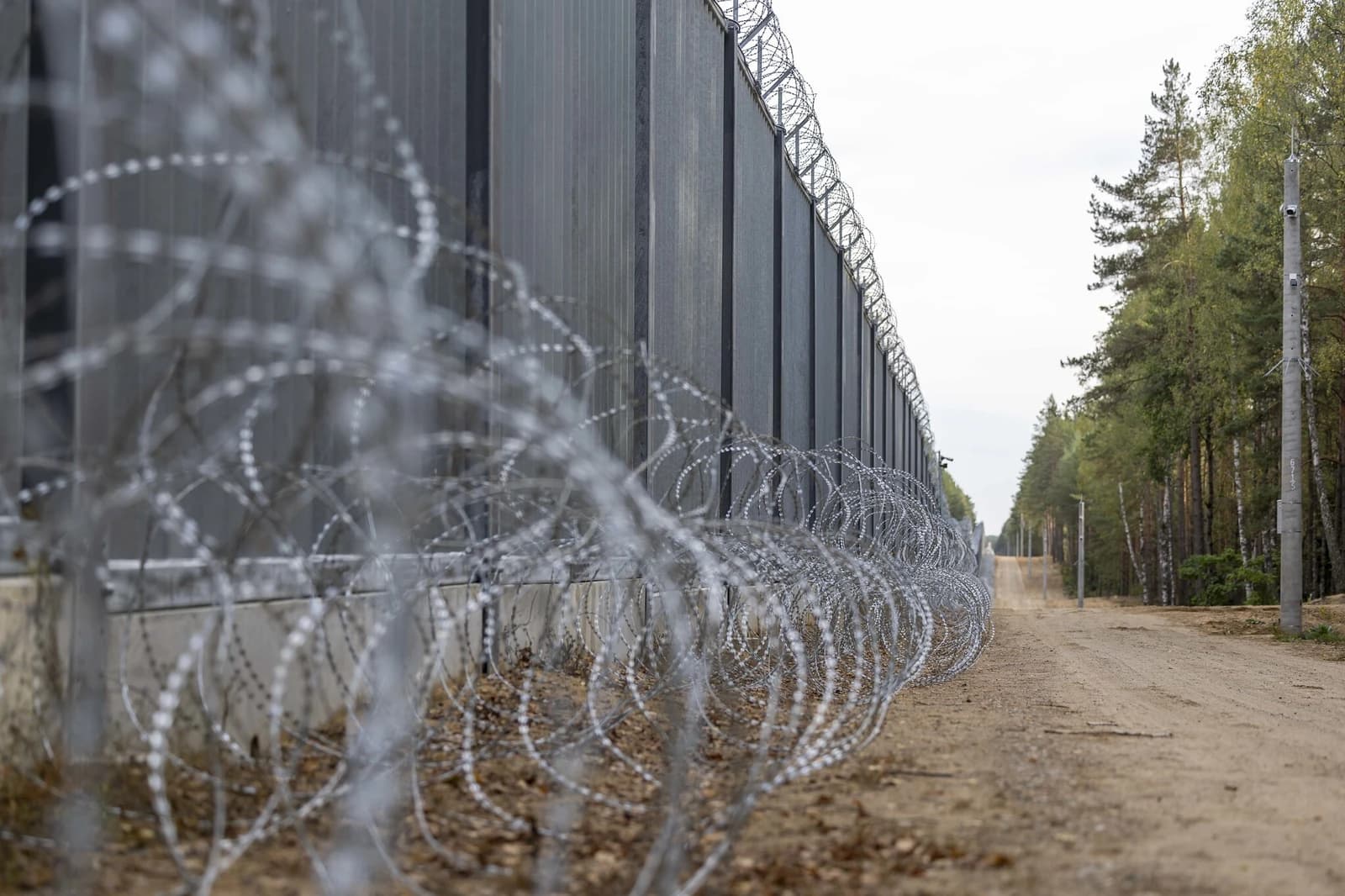 A close-up view of the Poland-Belarus border barrier featuring razor wire.