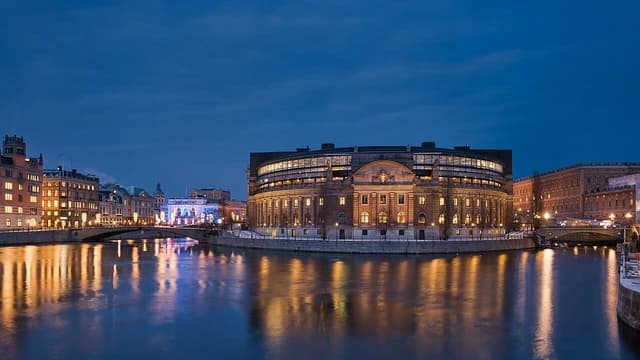 Riksdagshuset, Parliament House, in Stockholm, Sweden, illuminated at night along the water.