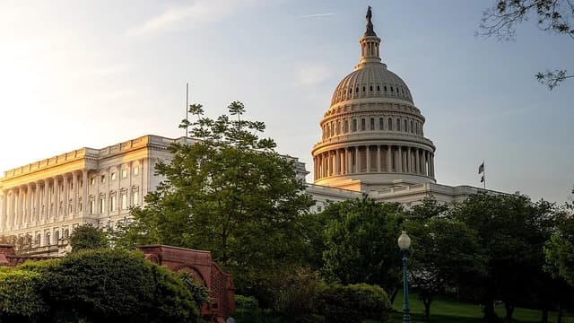 The United States Capitol Building and grounds under a clear sky during sunrise.