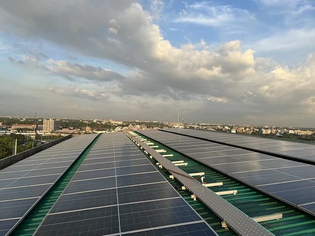 Rooftop solar panels installed on a commercial building, city visible in distance.