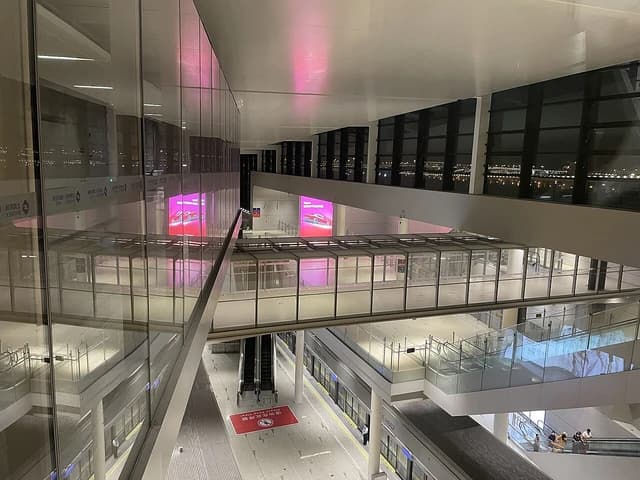 APM train station with glass walls and escalators at Shanghai Pudong International Airport.