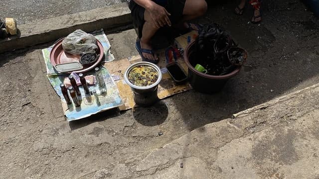 Herbalist vendor selling bottles and containers of traditional medicine products.
