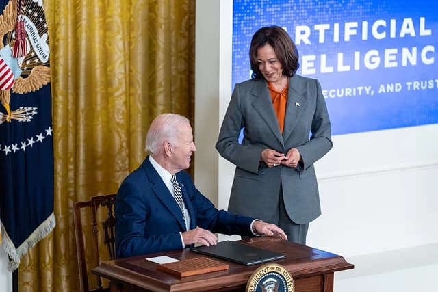 President Joe Biden signing an Executive Order on AI, with Vice President Kamala Harris standing nearby.