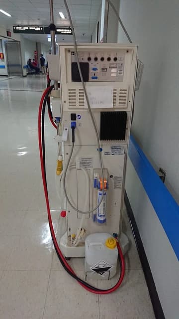 Hemodialysis machine with tubes and a liquid container in a hospital.