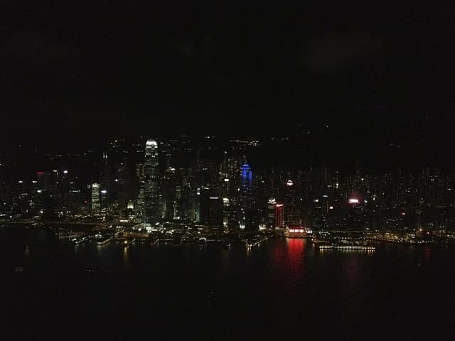 Overview of Hong Kong's illuminated financial district and Victoria Harbour at night.