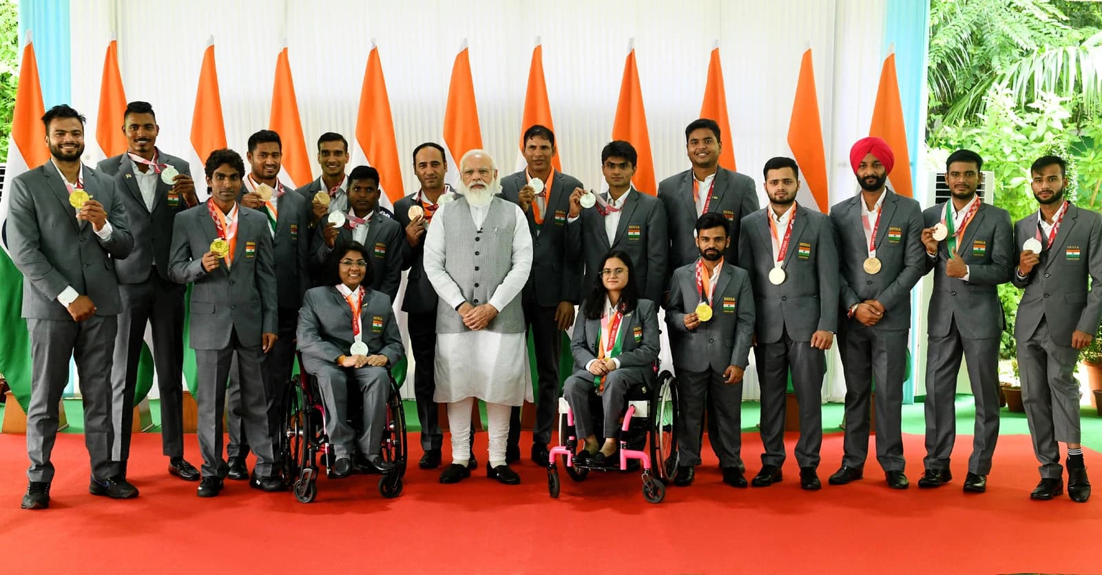 Prime Minister Narendra Modi standing with the Indian Paralympic team holding medals.