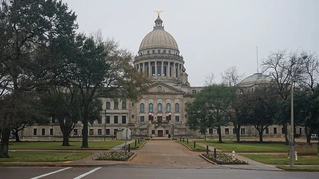 Mississippi State Capitol Building with its large dome, surrounded by trees.