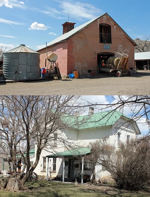 Farm buildings, including a brick barn, grain silo, and a white house with a green roof.