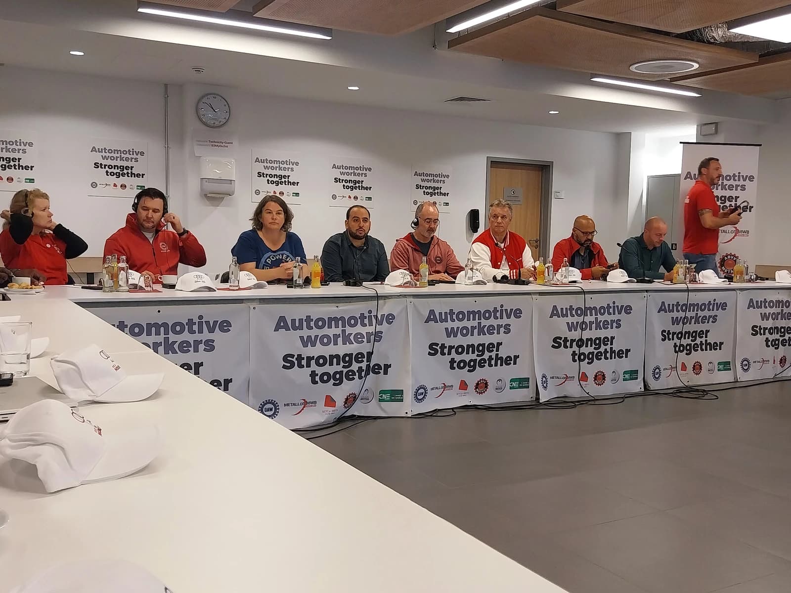 Representatives from labor unions UAW and IndustriALL Europe sit at a table for a press conference.