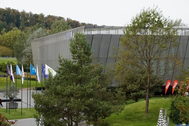 FIFA headquarters building with trees and various flags flying on poles.