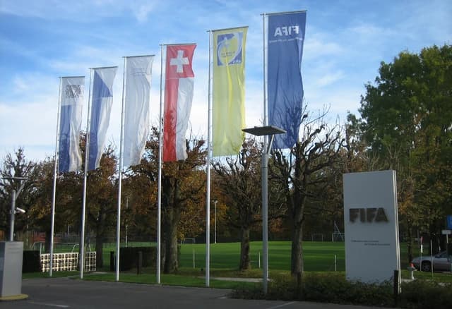 Entrance to FIFA headquarters with multiple flags flying and a sign on the right.