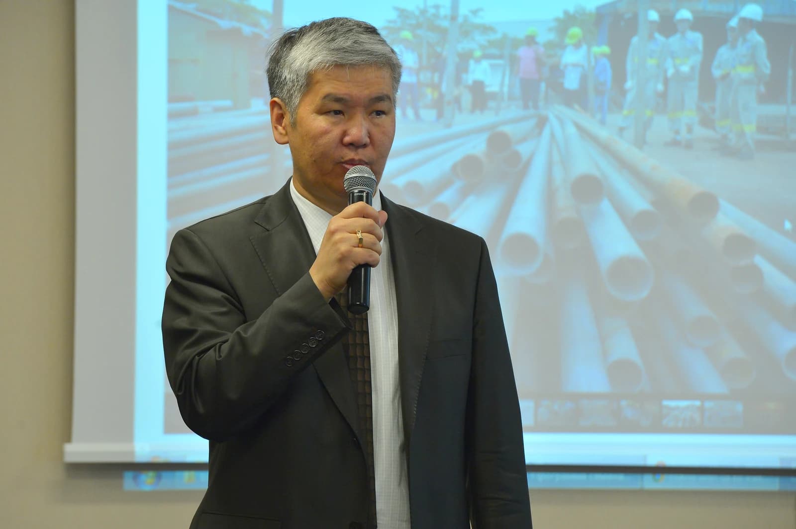Marat Shaldybayev, expert, speaking at a conference with a presentation screen behind him.