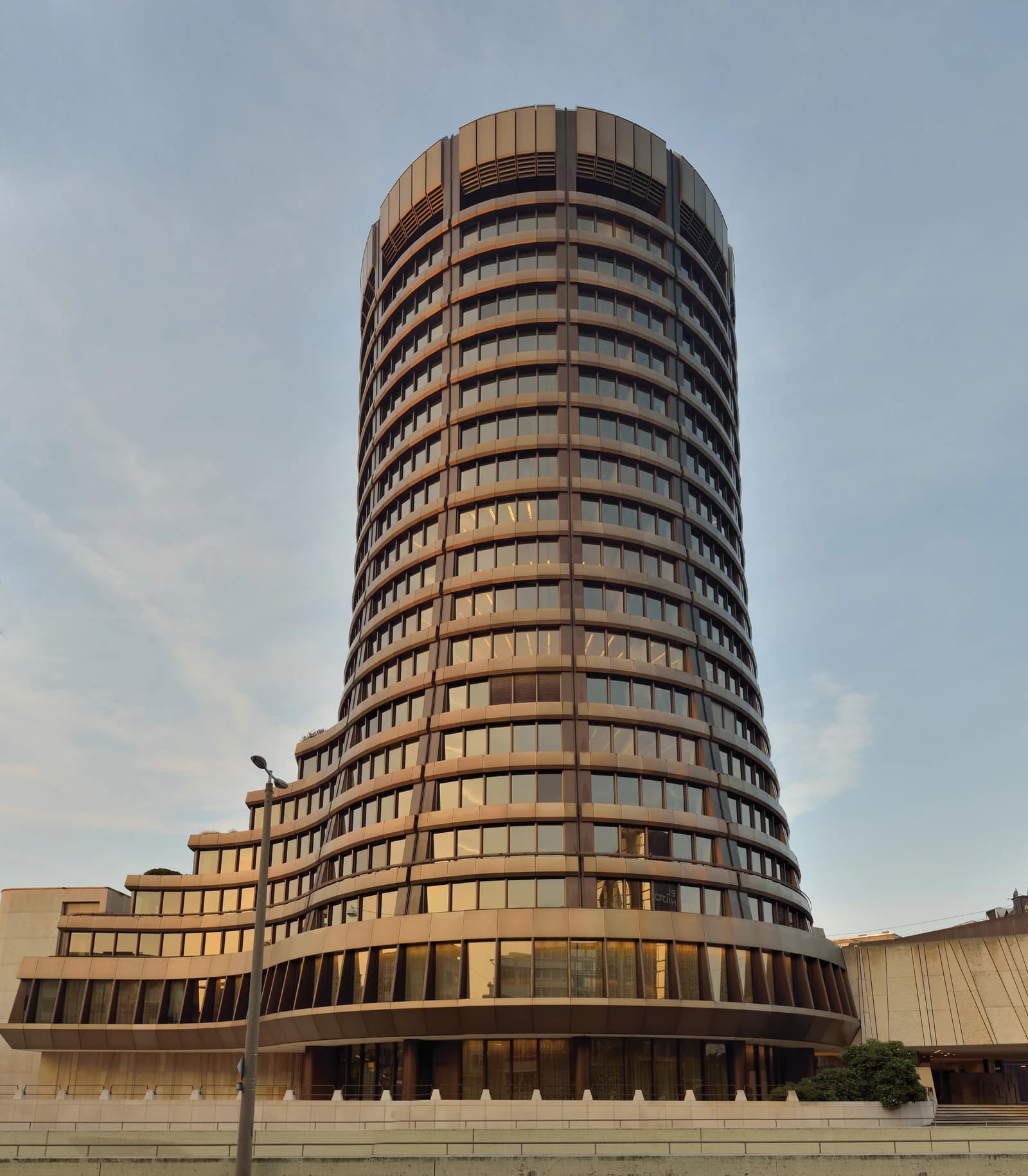 Bank for International Settlements headquarters building with round main tower and terraced wings.