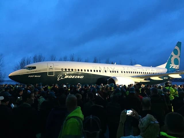 Boeing 737 MAX aircraft on the tarmac surrounded by a large crowd of people.