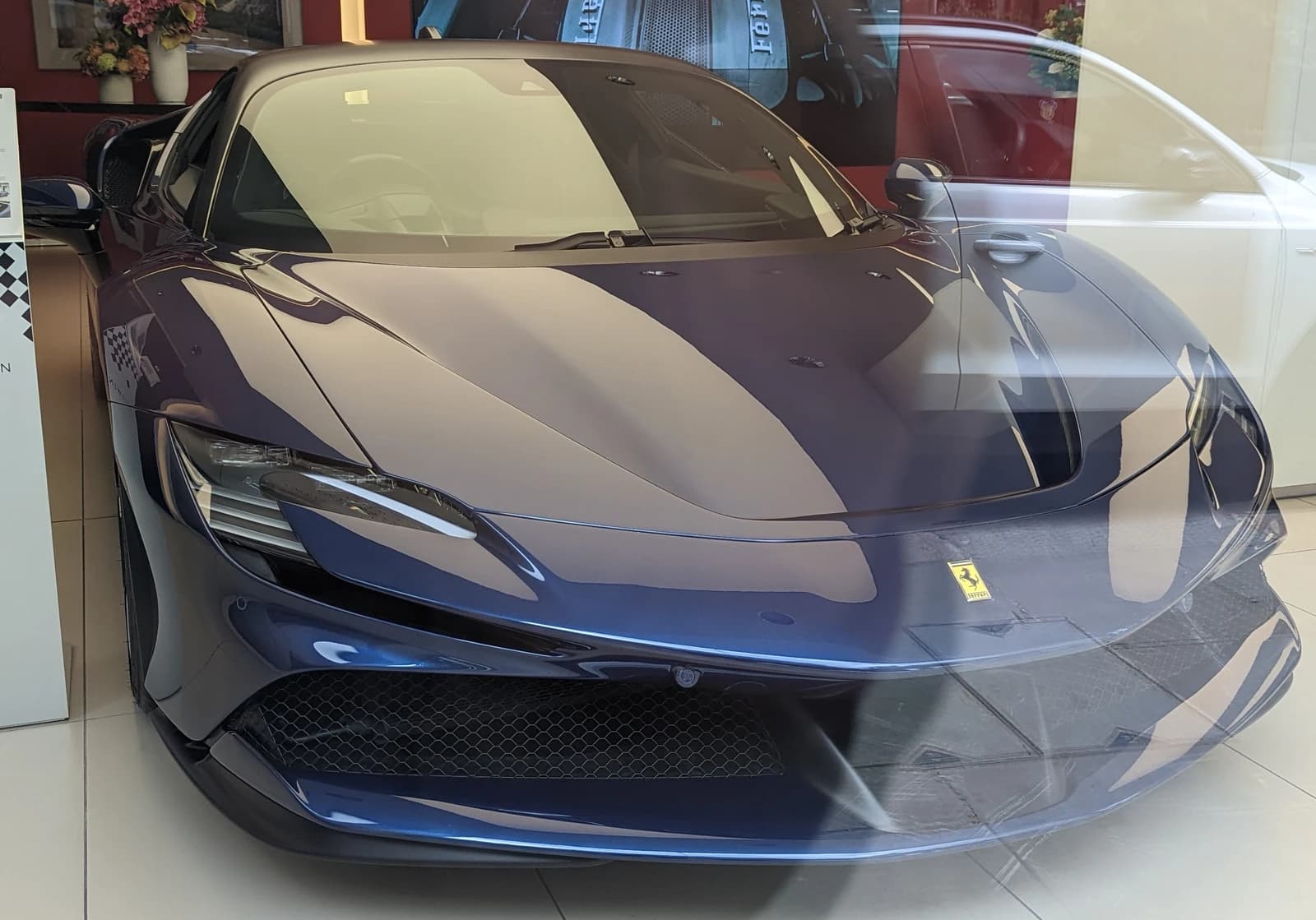 Dark blue Ferrari SF90 sports car in a showroom.