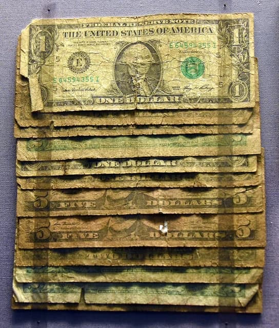Stack of heavily worn US dollar banknotes on display at the British Museum.