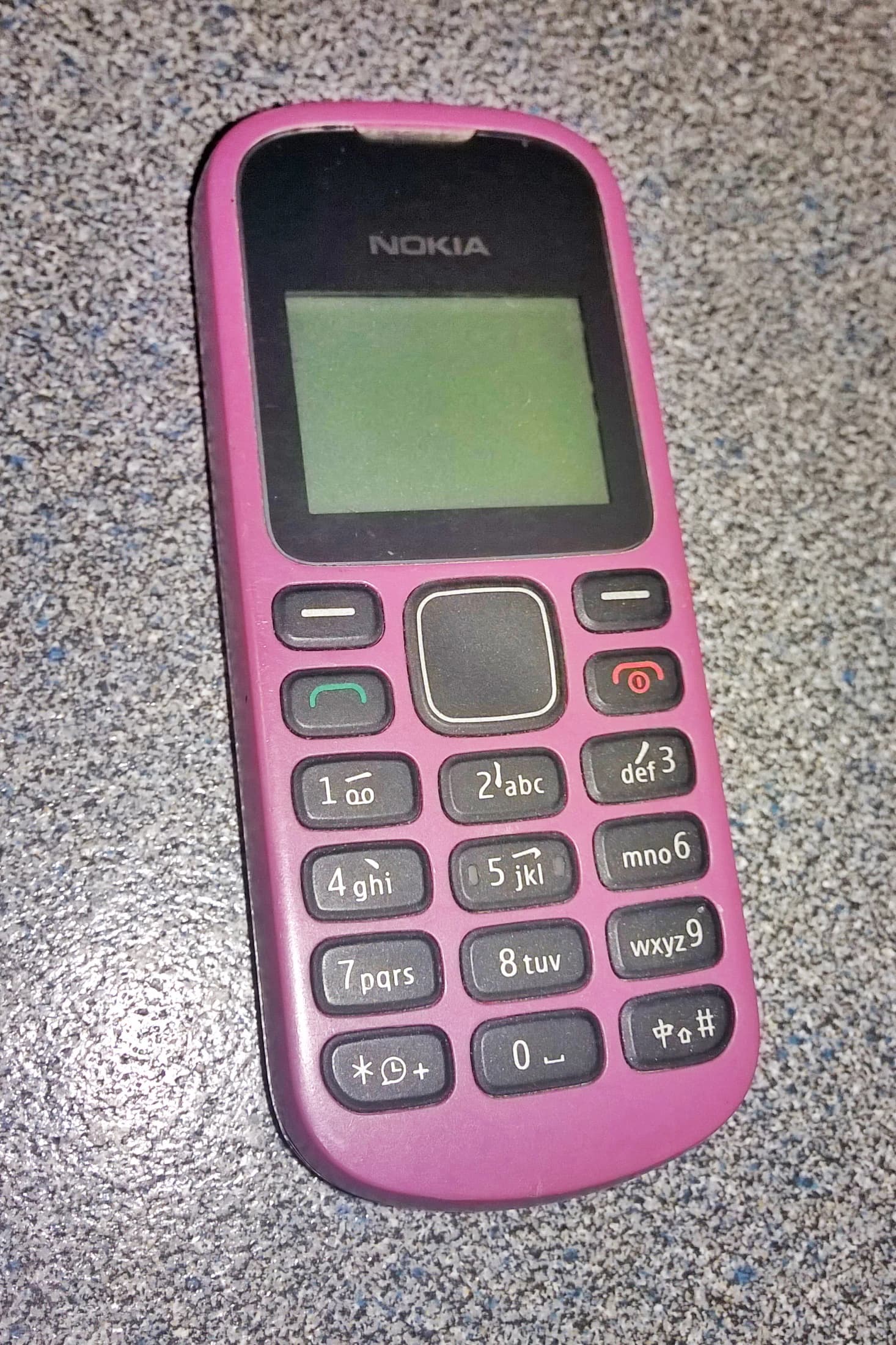 Pink Nokia mobile phone with a green screen and T9 keyboard.