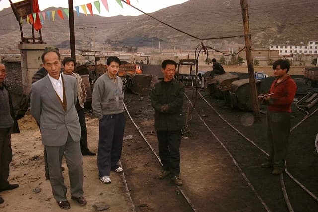 Group of men standing next to mining equipment at Lao Ye Temple Mine in China.