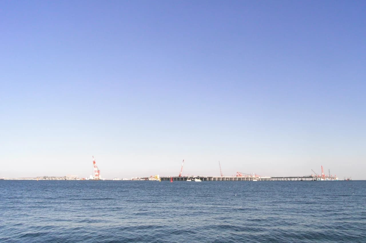Construction cranes and structures of a new runway extending into the water.
