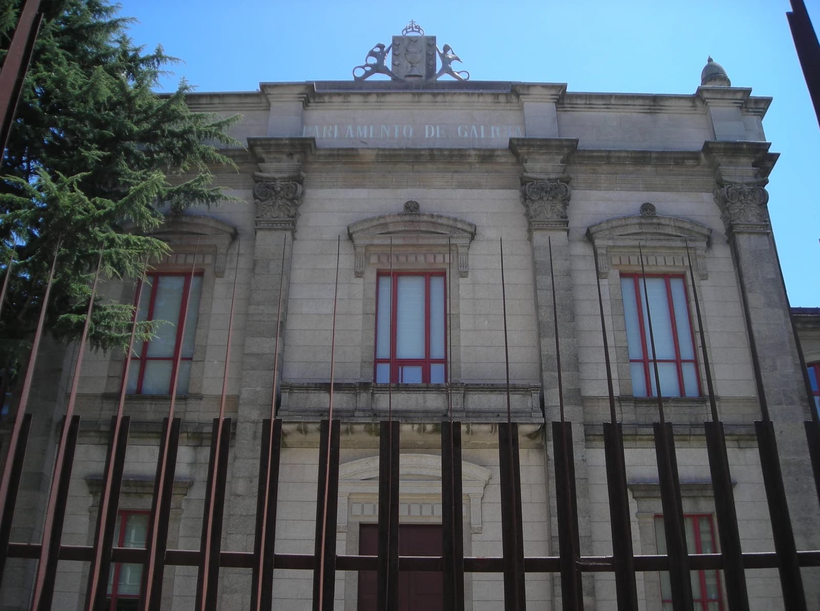 Exterior of the Parliament of Galicia building with a coat of arms at the top.