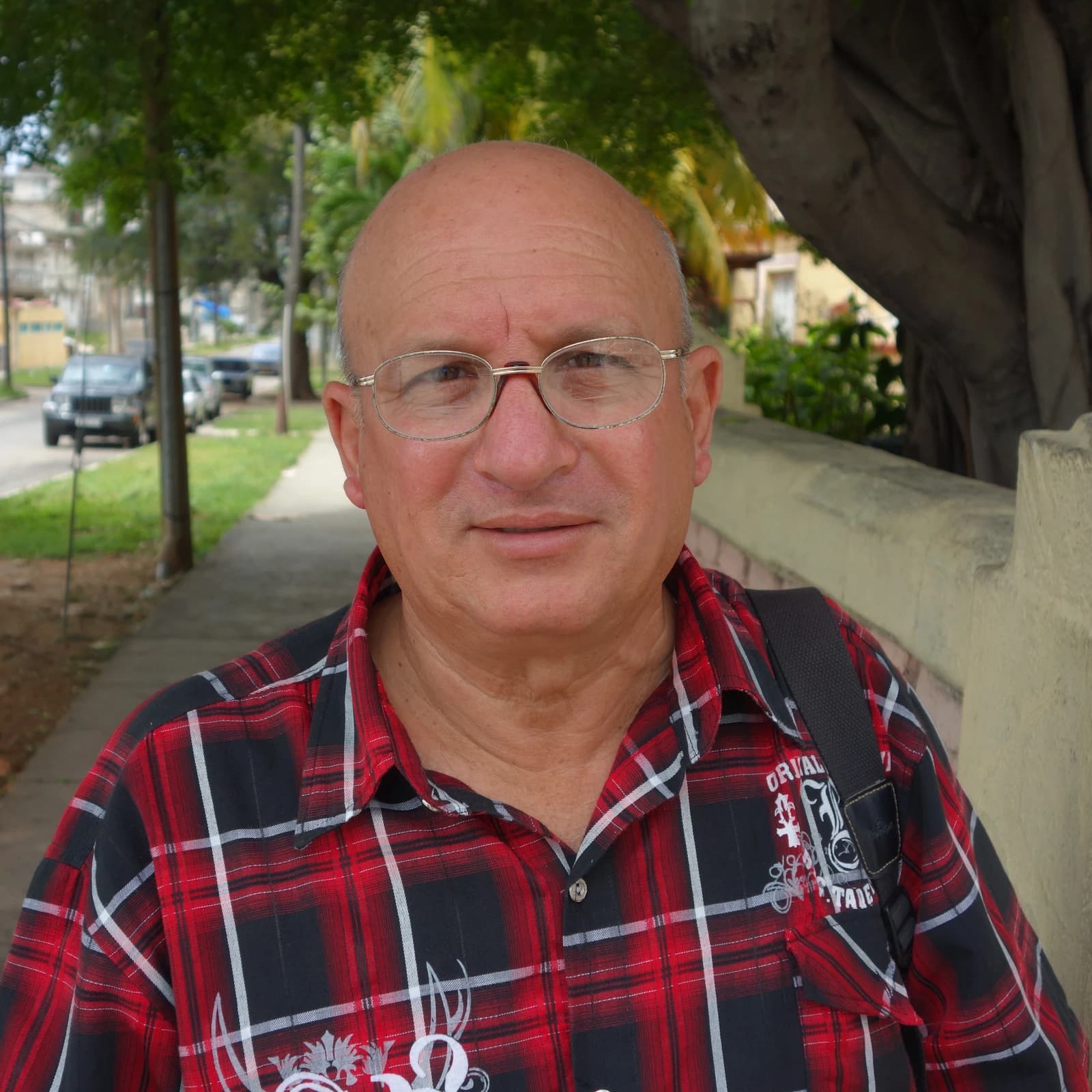 Félix Navarro Rodríguez, Cuban opposition leader, stands on a sidewalk next to a wall.