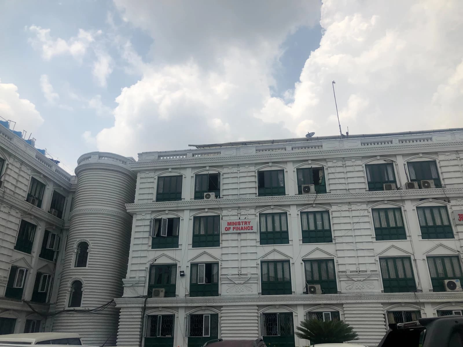 White building with green-framed windows and a sign reading "Ministry of Finance."