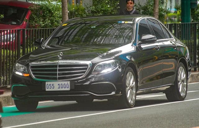 Black Mercedes-Benz E-Class sedan driving on a city street.