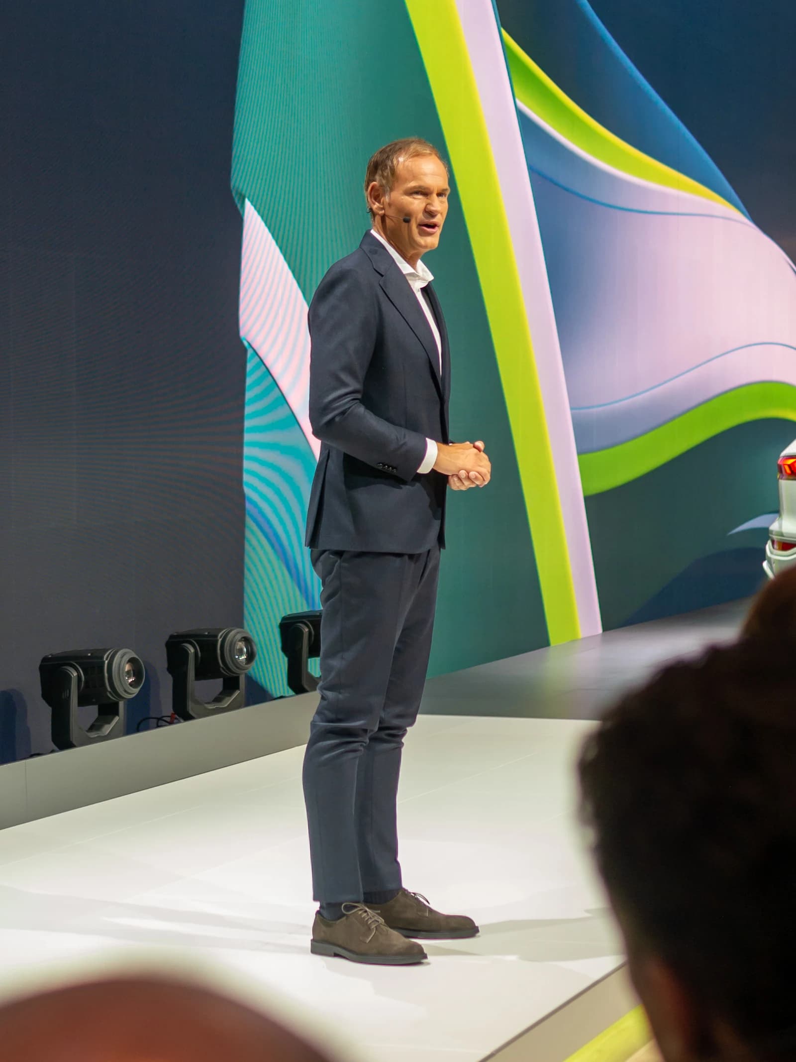 Oliver Blume, CEO of Volkswagen Group, speaking on stage at a conference.