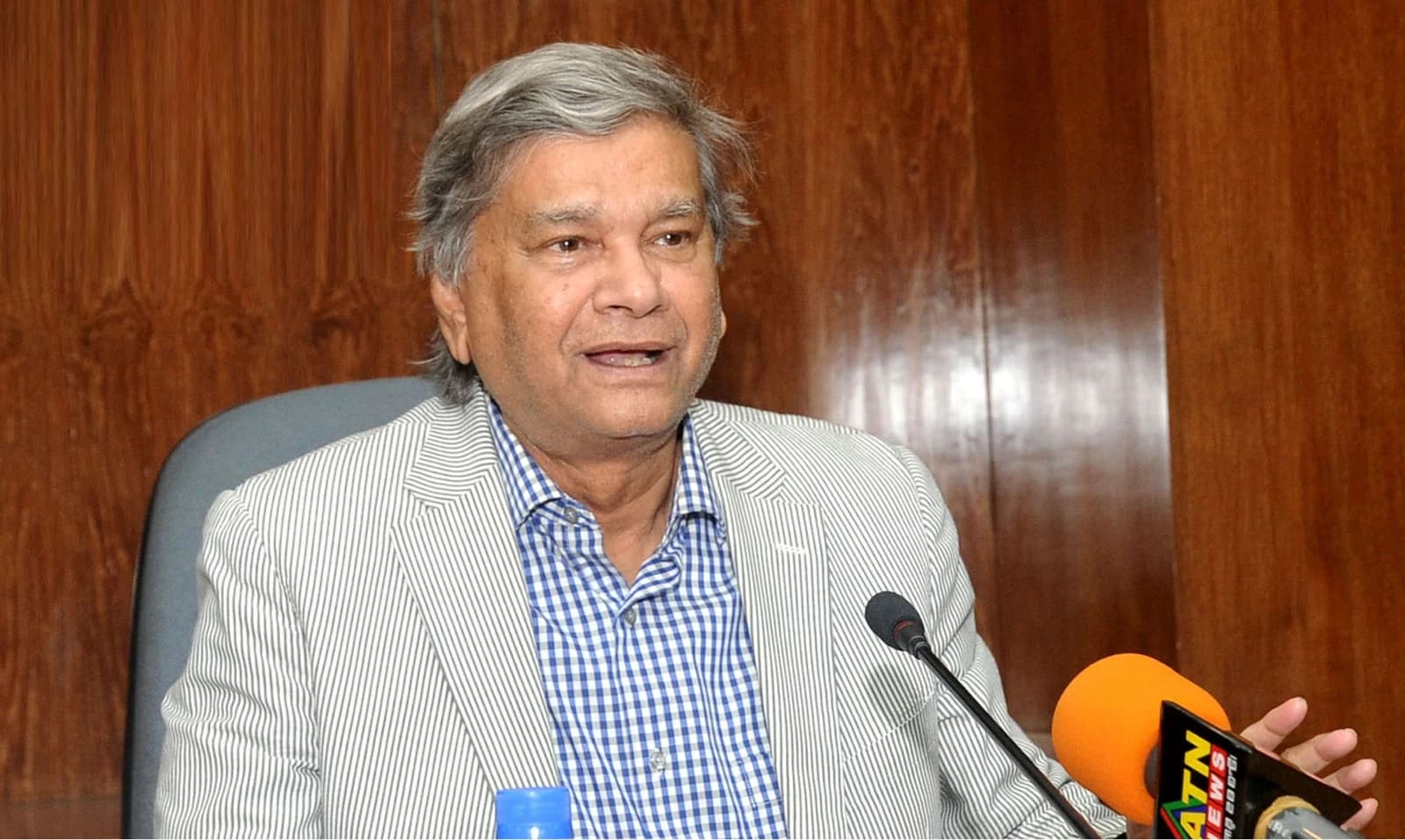 M A Mannan, Minister of State for Finance, speaking into microphones at a press conference.