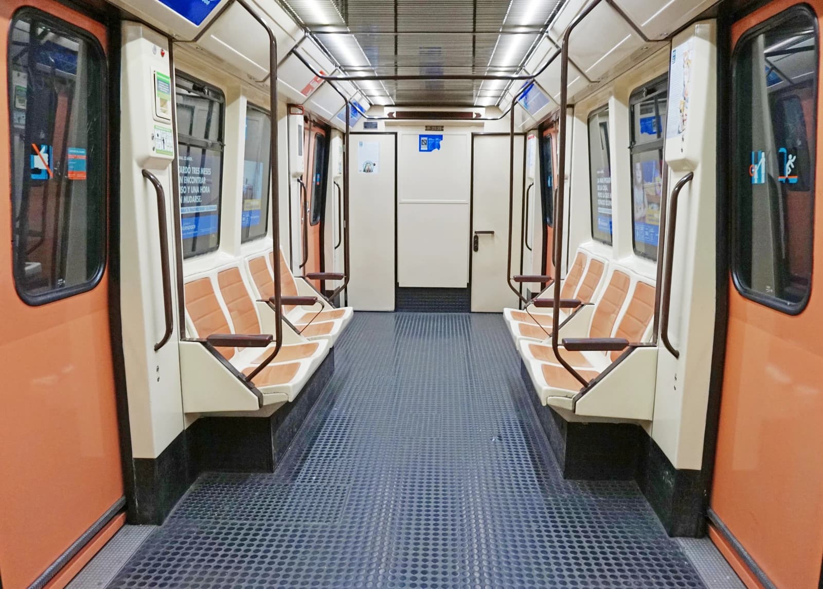 Interior of a Madrid Metro subway car with orange and white seats.