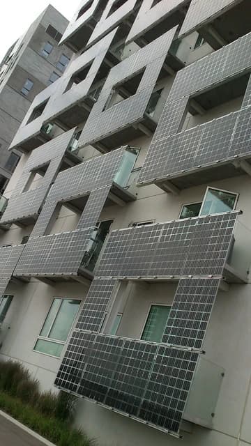 Photovoltaic panels integrated into the design of a building facade, likely in a city setting.