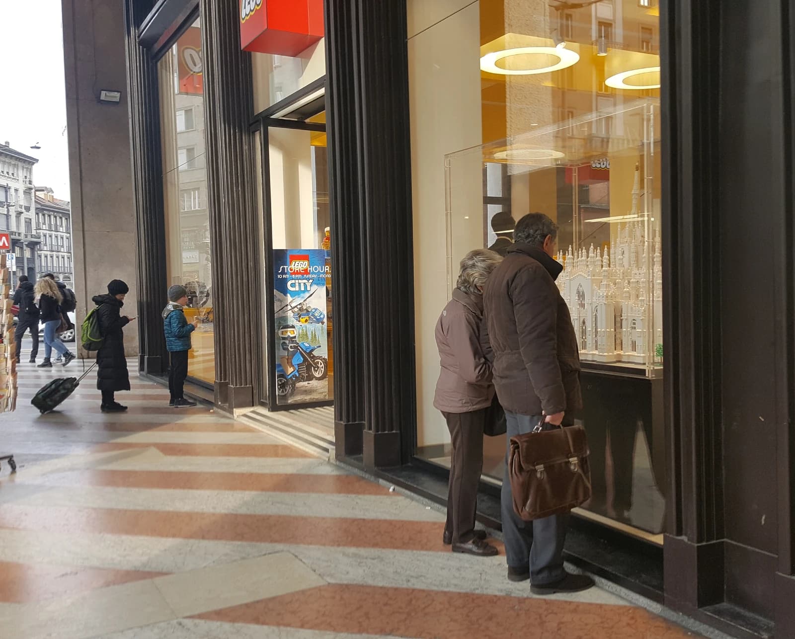People stand outside a store, looking into a display window.