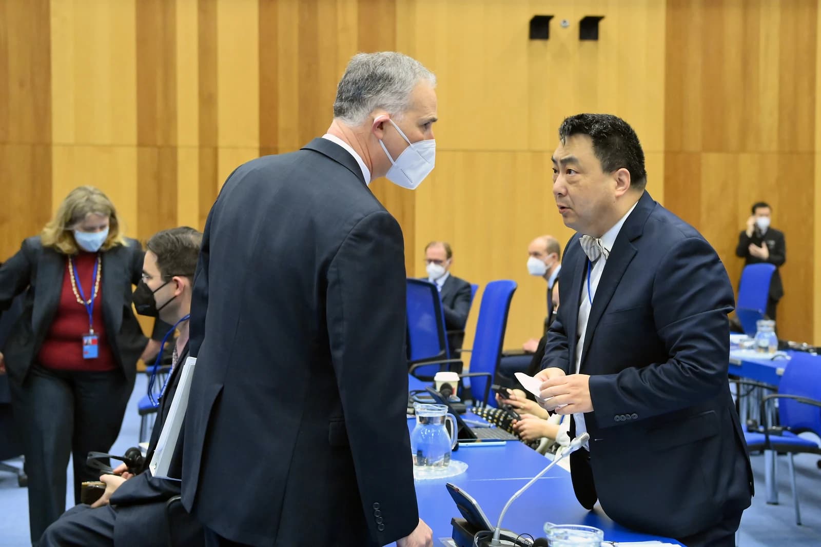 Louis L. Bono, senior adviser, talks with Wang Qun, Chinese envoy, at a meeting.