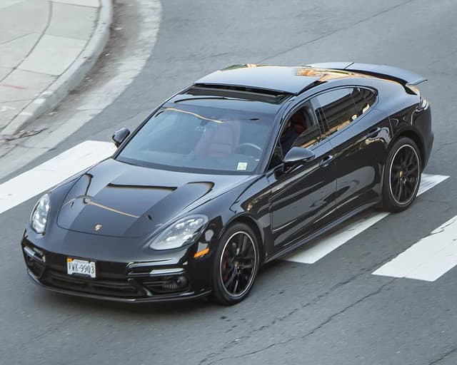 Black Porsche Panamera Turbo car driving on a street, seen from above.