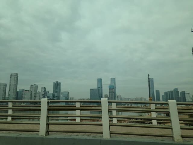 Skyline of modern buildings and a bay area in Shenzhen, China under a cloudy sky.