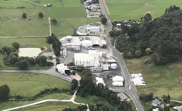 Aerial view of a Fonterra dairy processing plant surrounded by green fields and roads.