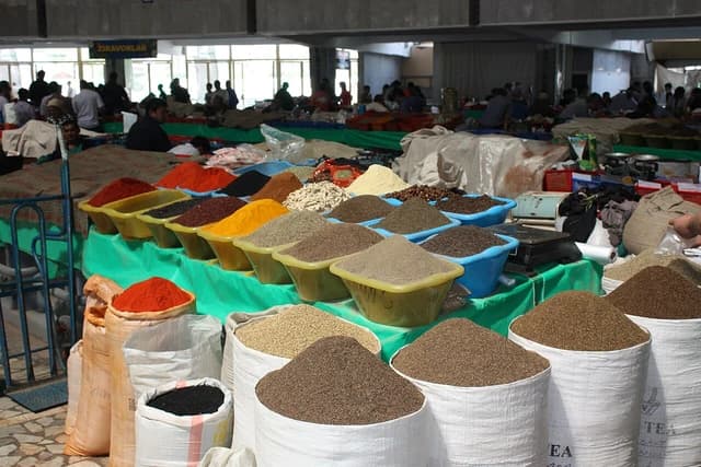 Colorful spices and grains in various containers and bags at a market stall.