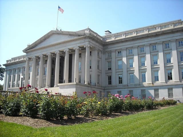 Rear view of the United States Treasury Department building, with a rose garden in the foreground.