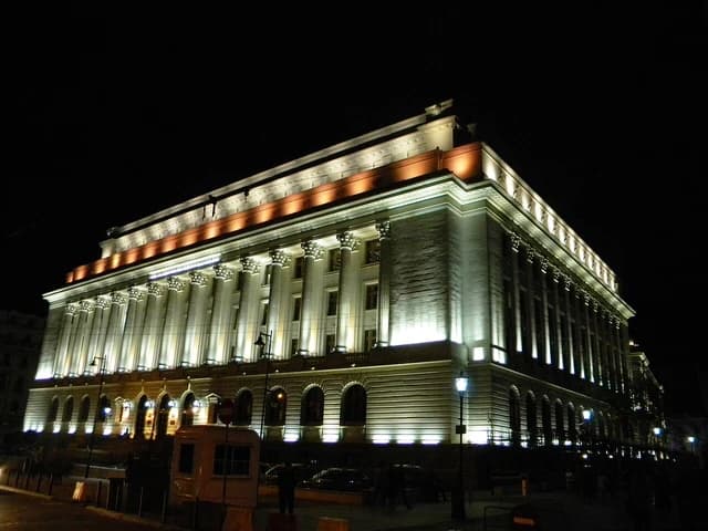 National Bank of Romania headquarters illuminated at night in Bucharest.