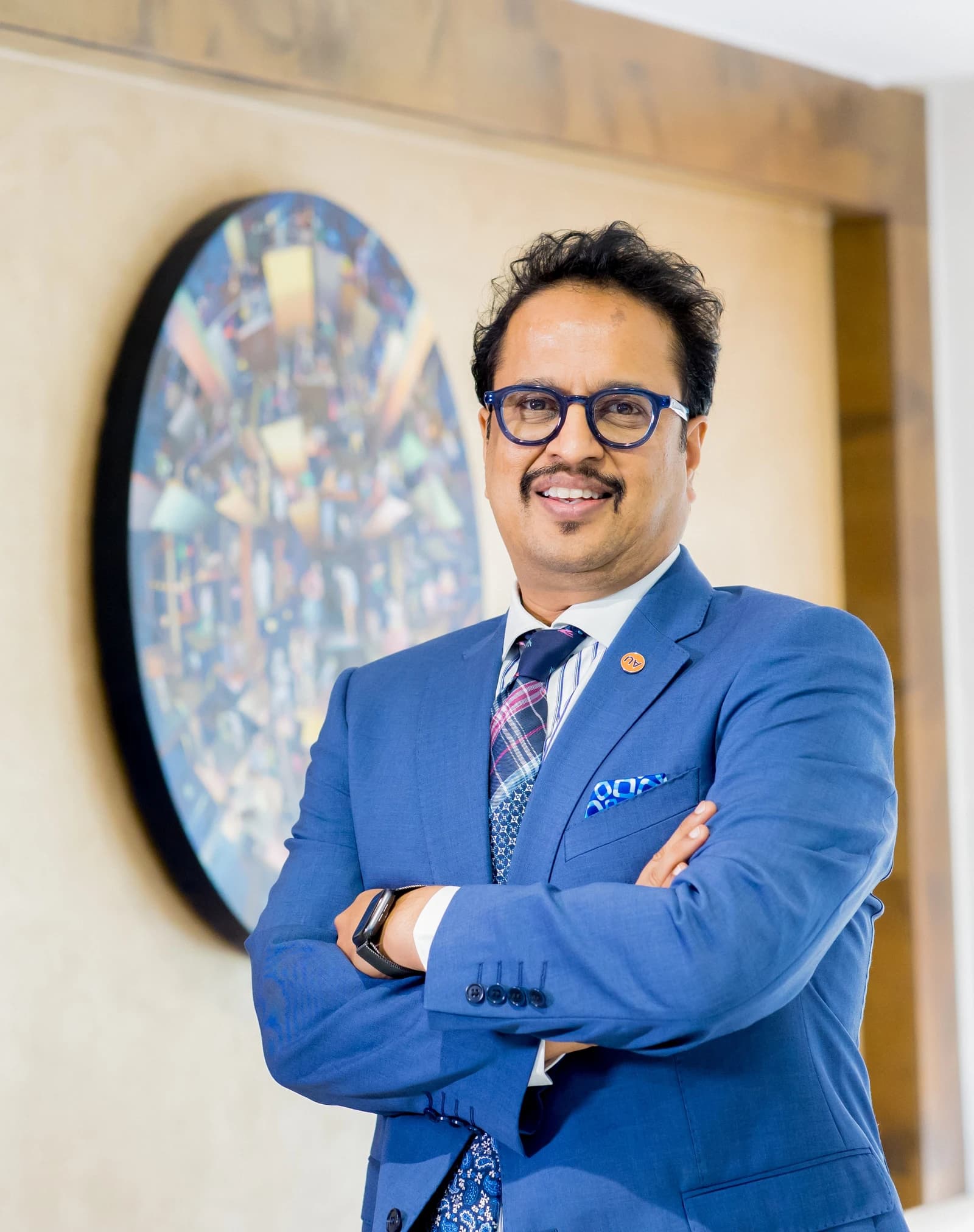 Sanjay Agarwal, MD & CEO of AU Small Finance Bank, standing indoors with arms crossed.