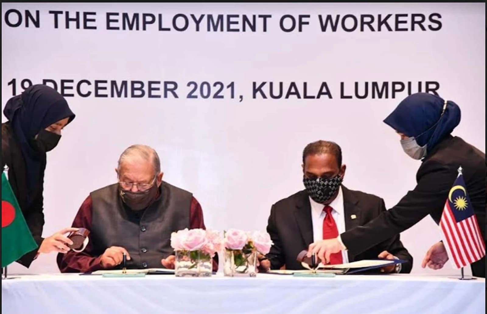 Officials from Malaysia and Bangladesh signing documents at a recruitment agreement ceremony.
