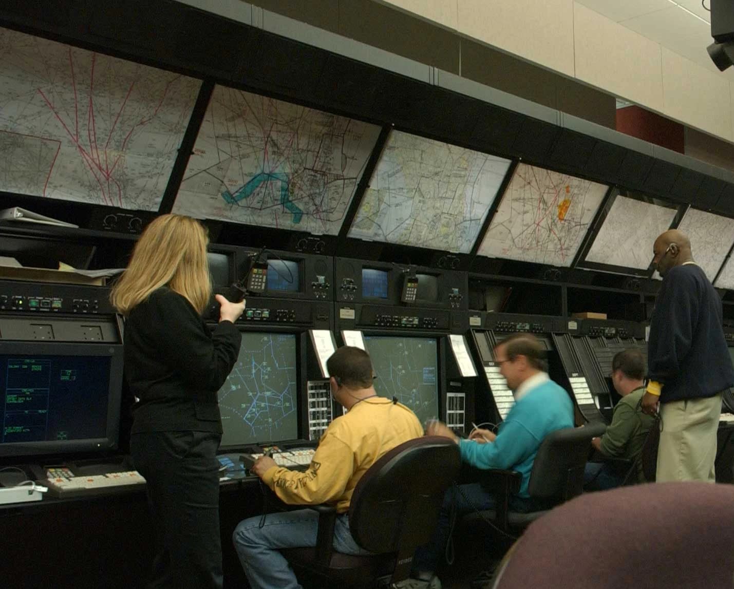 Several air traffic controllers monitor screens and communicate in a control center.
