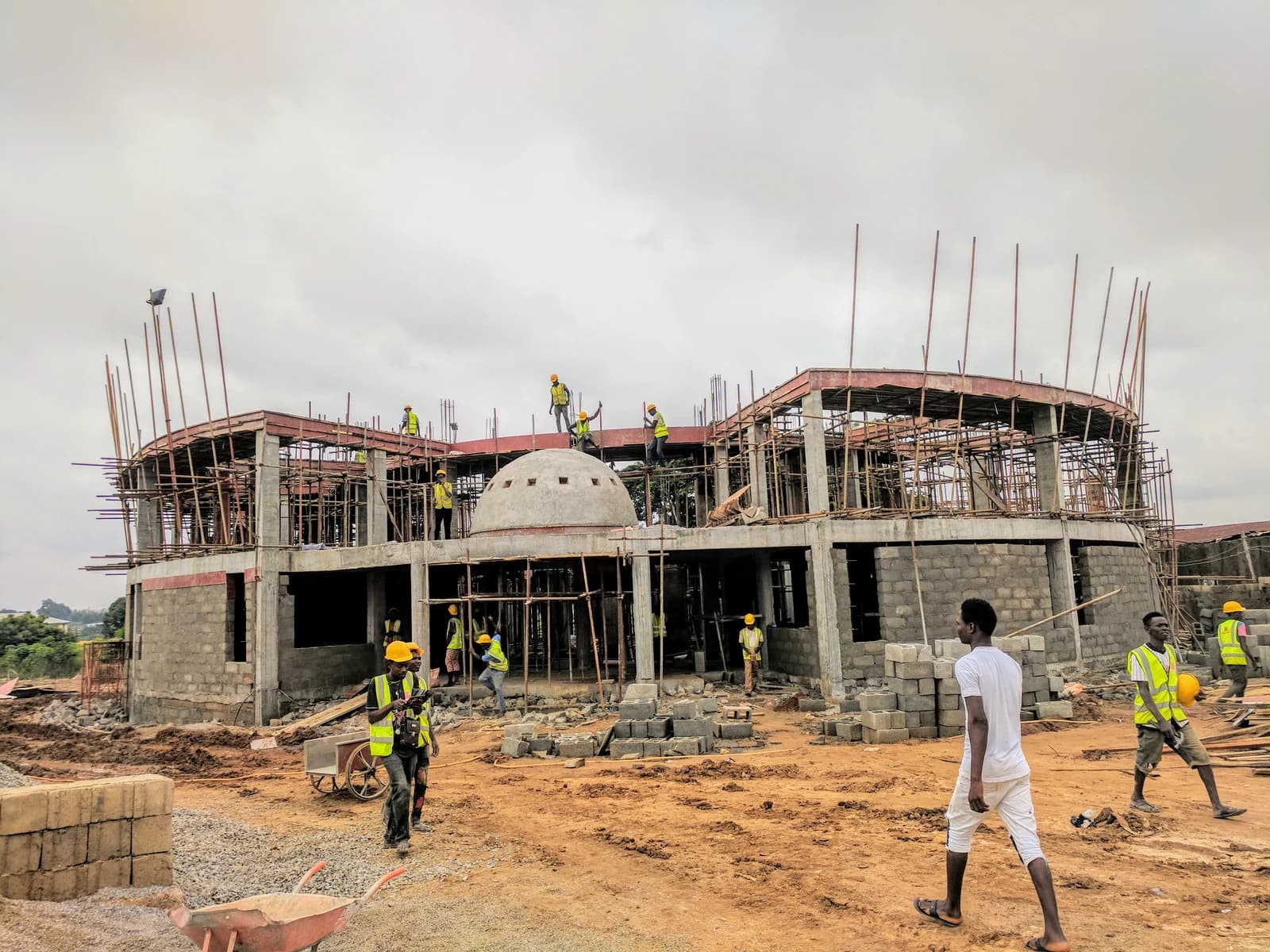 Bricklayers work on the walls and scaffolding of a large building under construction.
